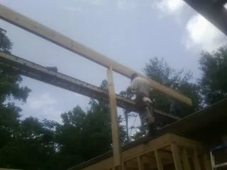 Carpenter setting a ridge beam over a new addition frame — Ice Dam Removal by Roofing Brothers in Guntown