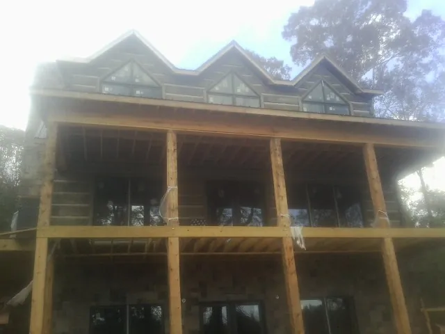 Dormers and porch framing on a large log home under construction — Roof Coating work by our crew in Guntown