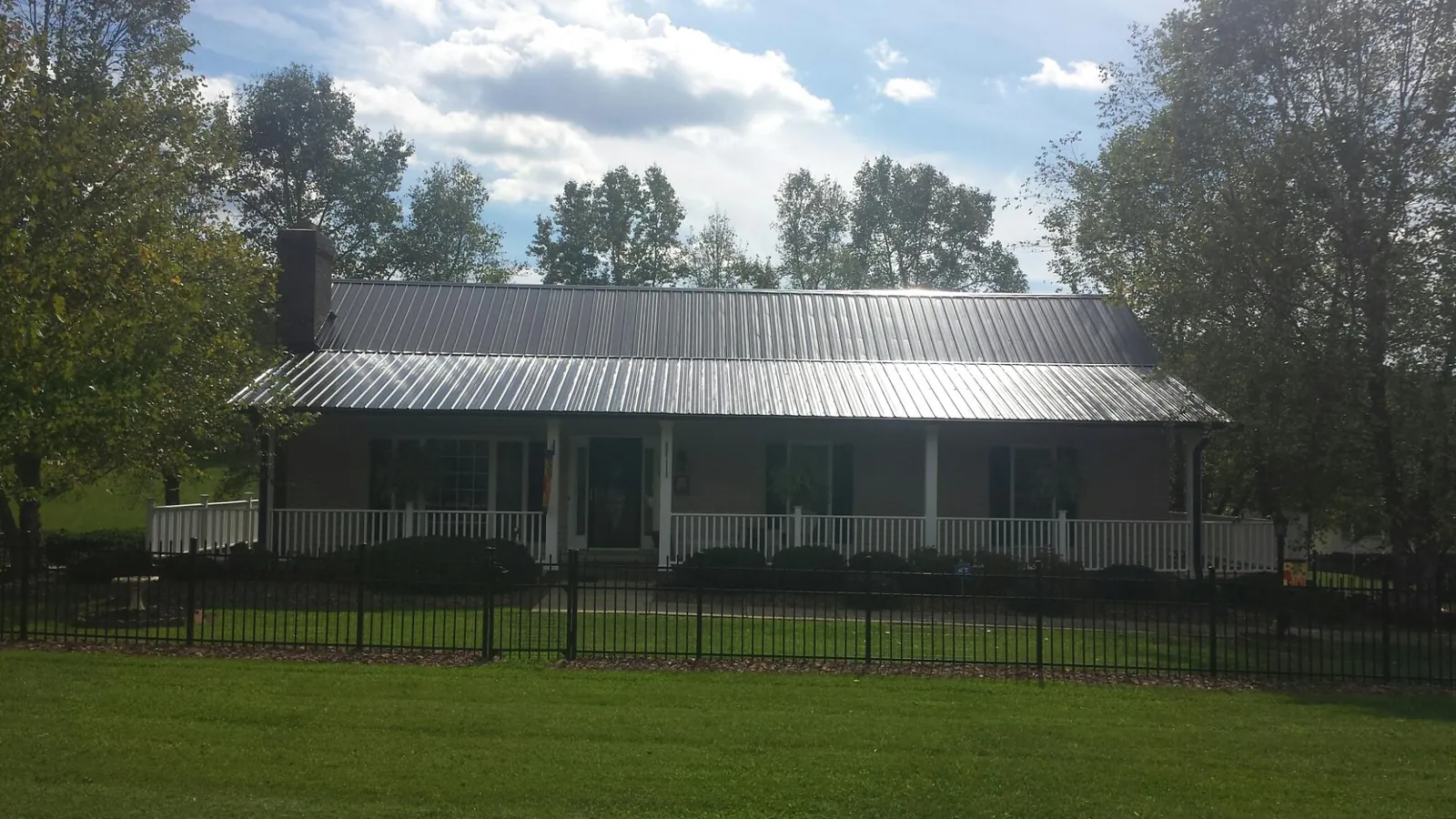 Gray metal roof on a brick ranch with a full width front porch — Gutter Guard Installation work by our crew in Guntown
