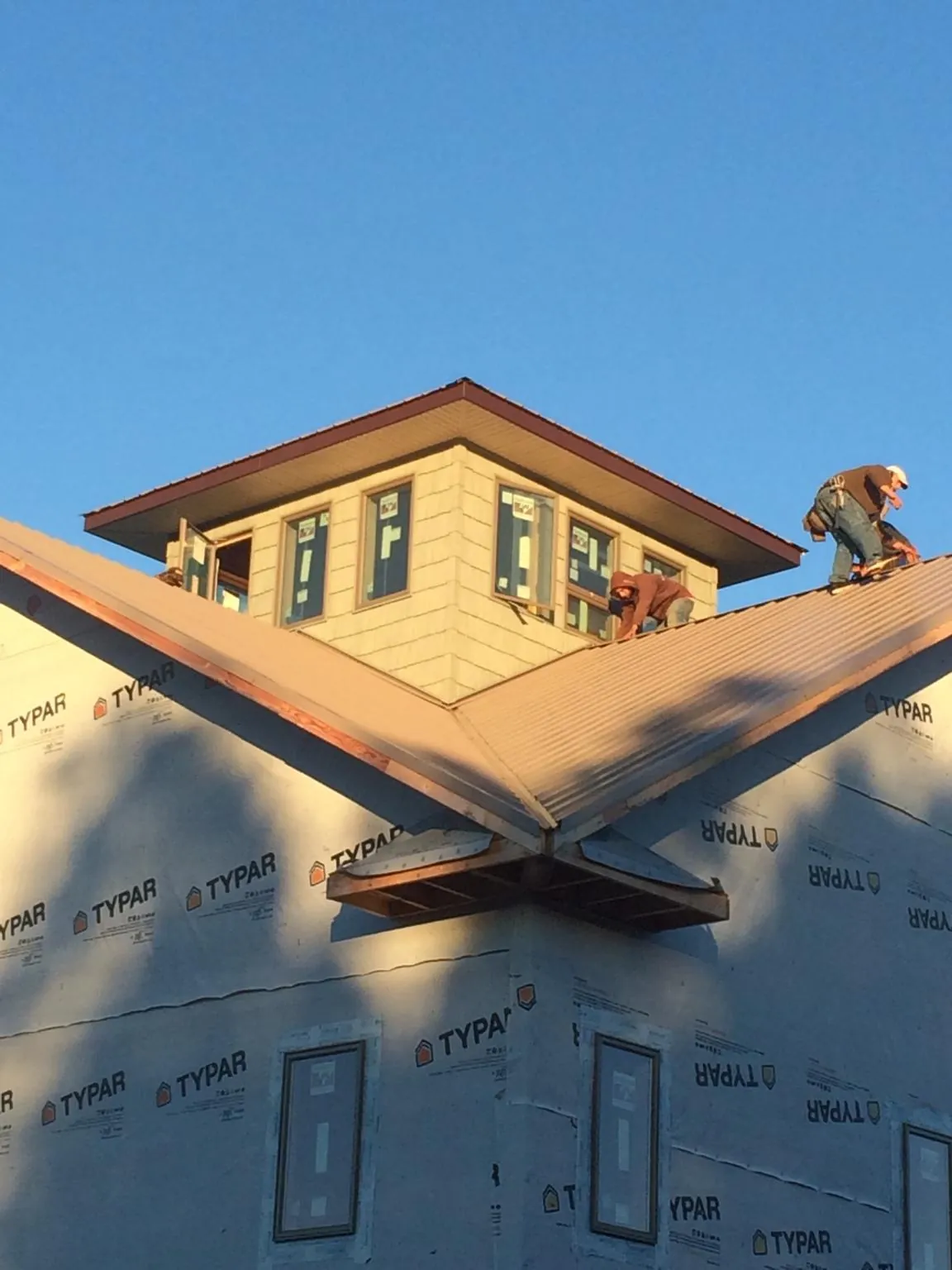 Roofers working around a rooftop cupola on a new metal roof at sunset — Roof Waterproofing in Guntown by Roofing Brothers